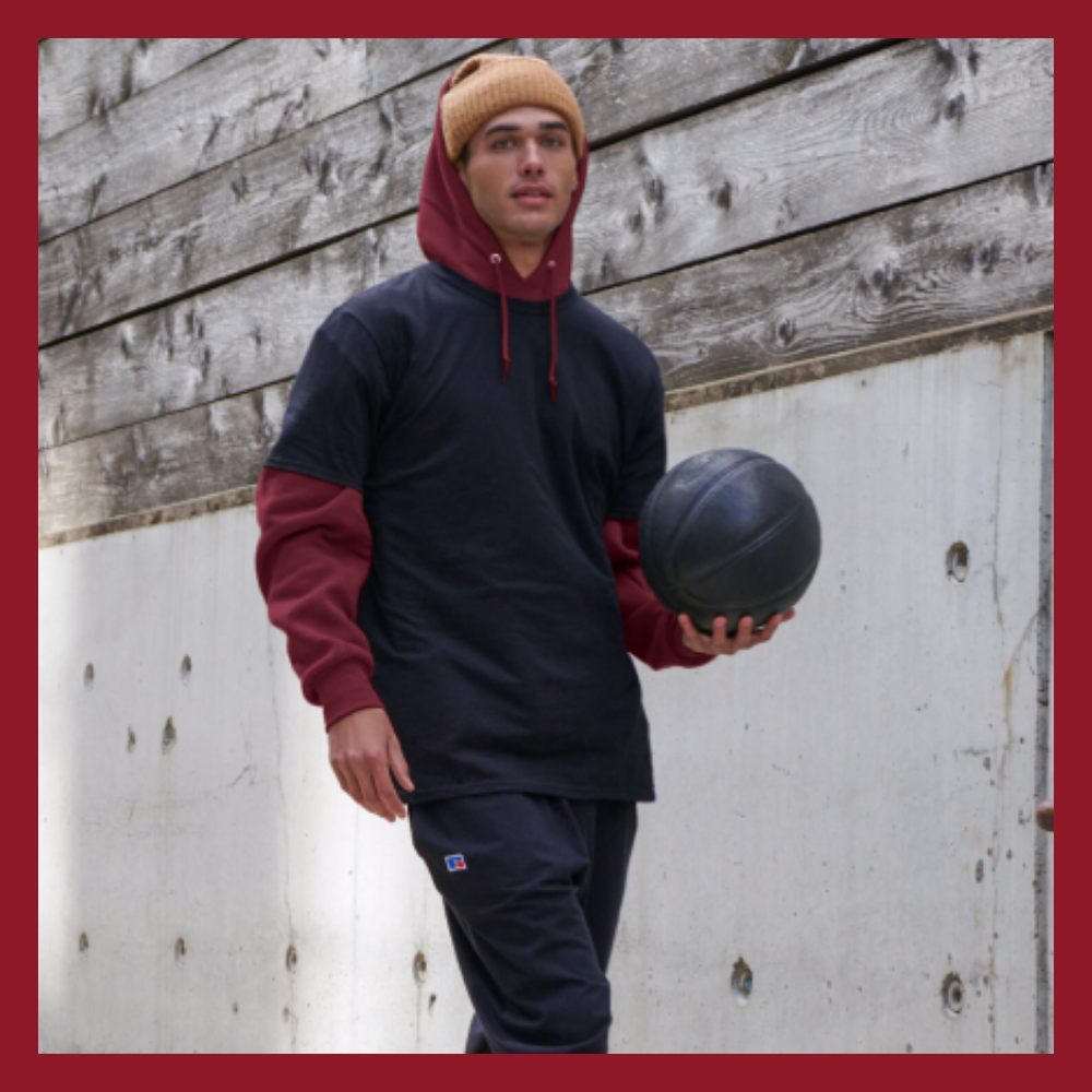 male model wearing russell athletic navy t-shirt over maroon hoodie sweatshirt and navy sweatpants